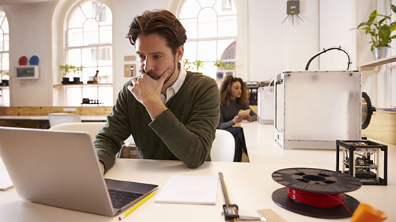 Man and woman in a design studio working on a laptop