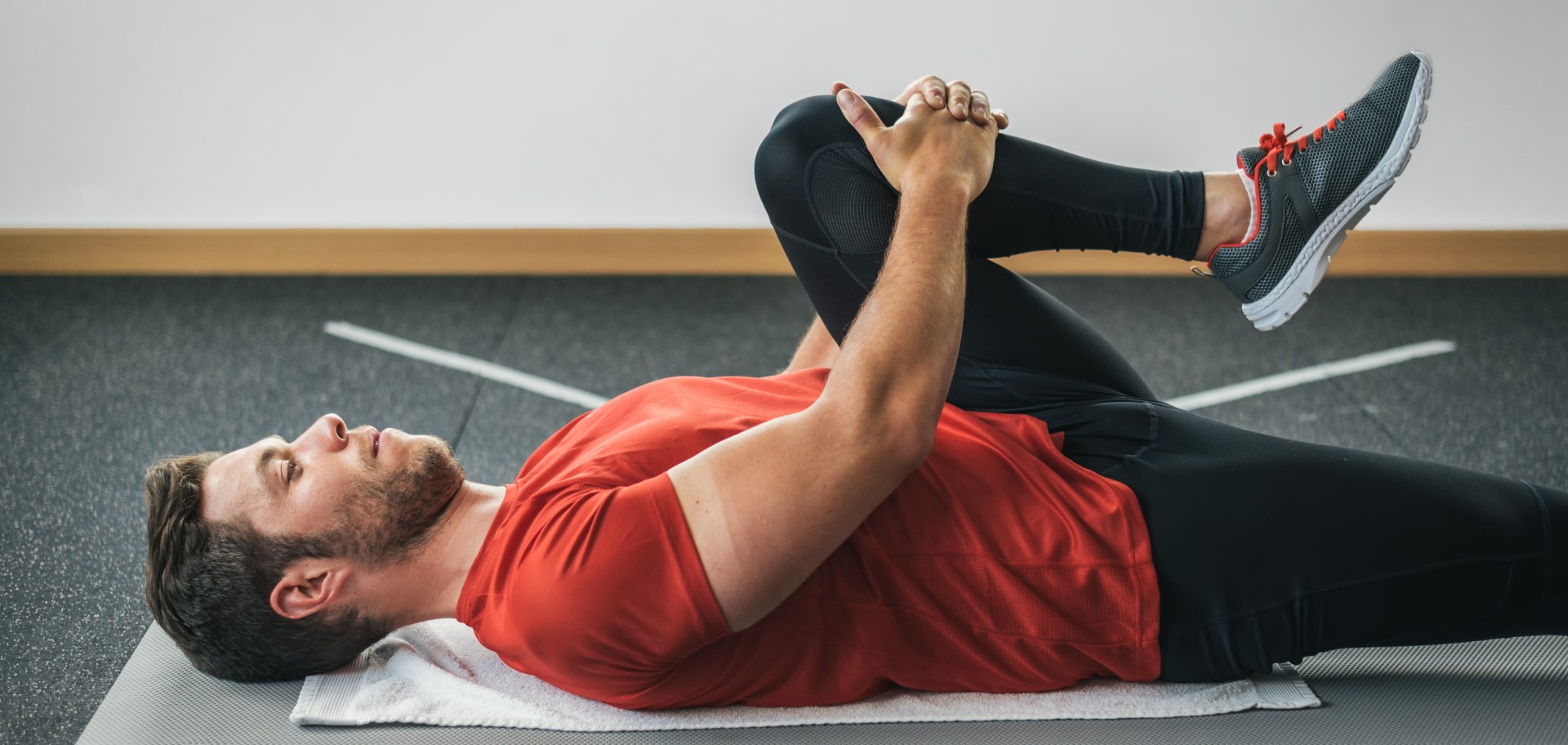 Man demonstrates a leg stretch while laying on his back