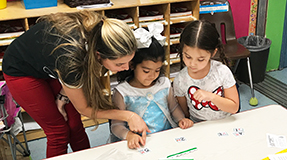 Teacher assisting two children