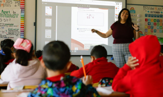 Teacher projecting a lesson on a screen for young students