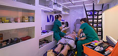 Two students practices CPR inside an EMT simulation.