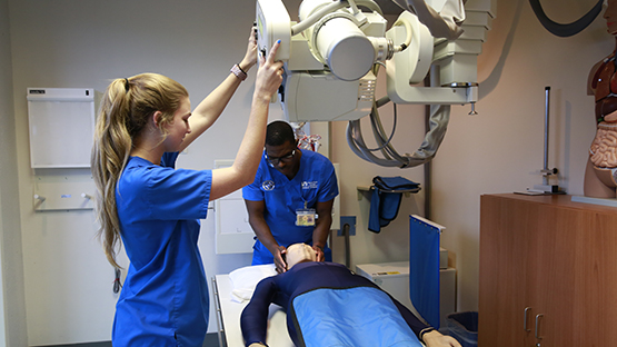 Radiography students taking x-ray of a patient